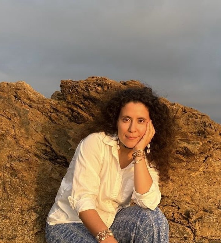 Sahara Al-Madi sitting on sunlit coastal rocks at golden hour